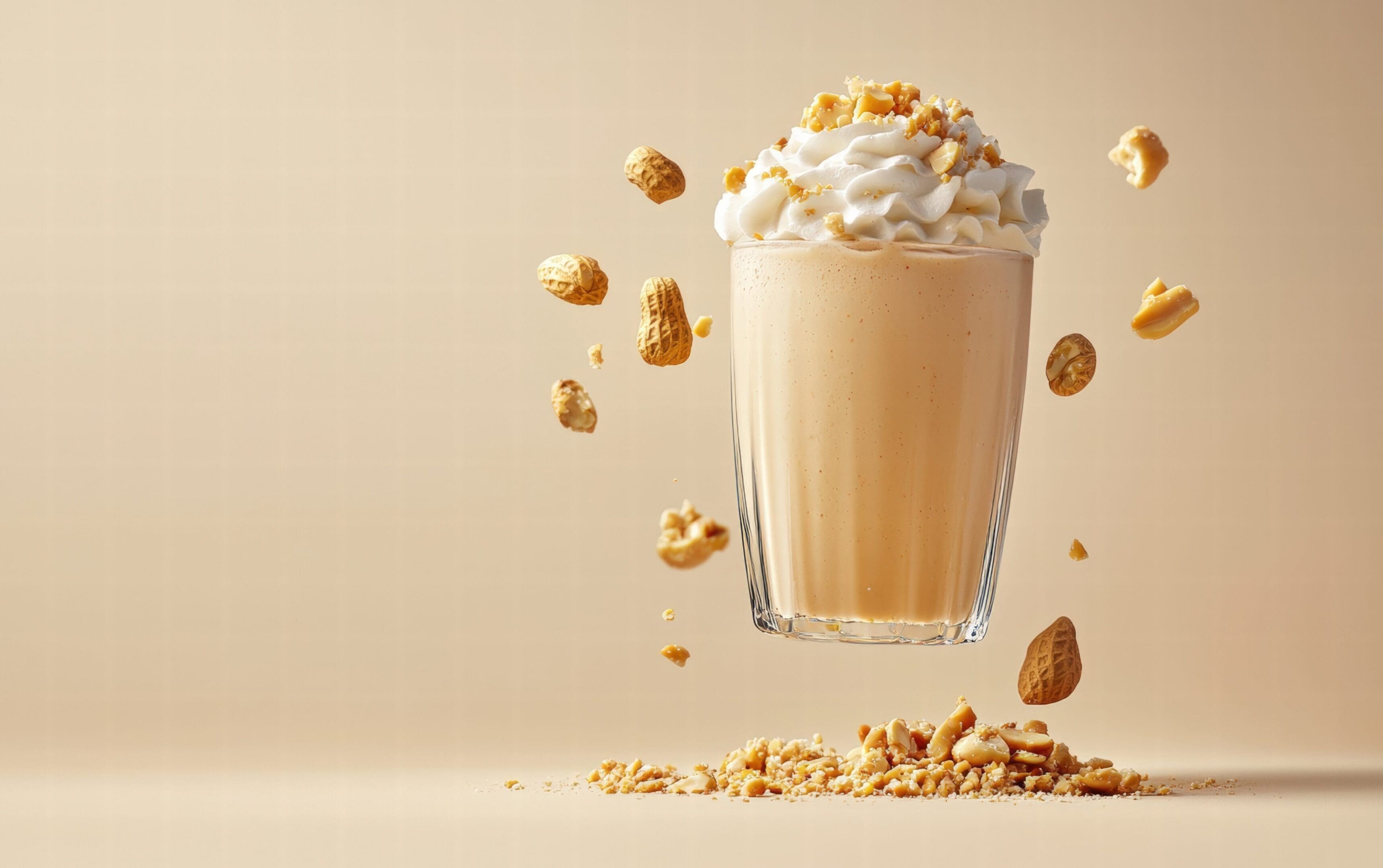 A creamy peanut butter milkshake levitating mid-air with peanut crumble and whipped cream, on a soft beige background
